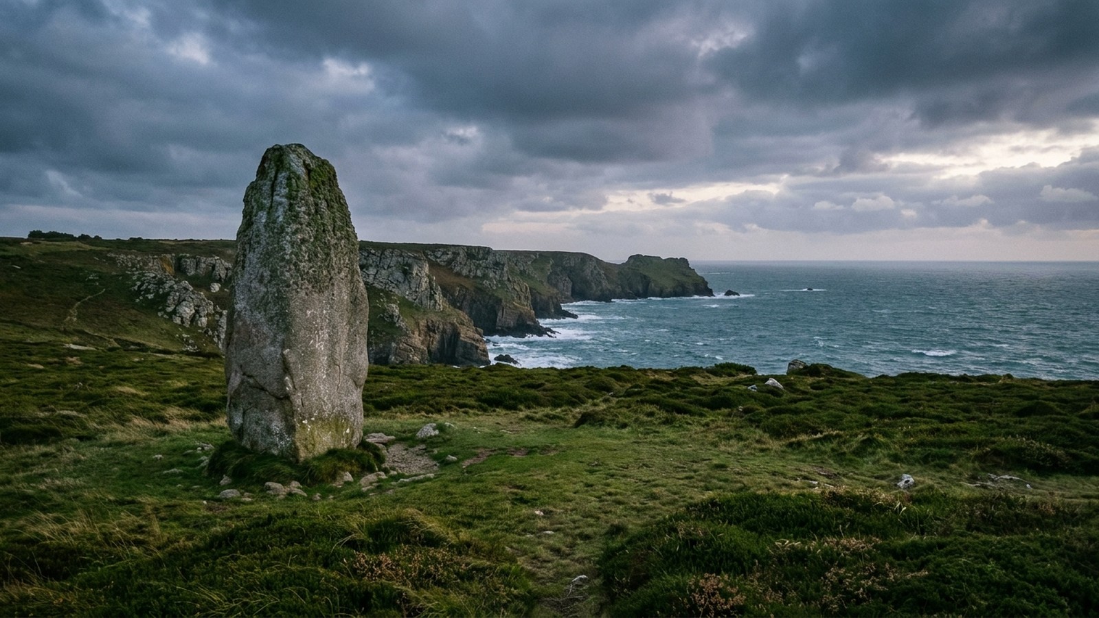 Côte sauvage de Bretagne au crépuscule avec un grand menhir dressé dans la lande