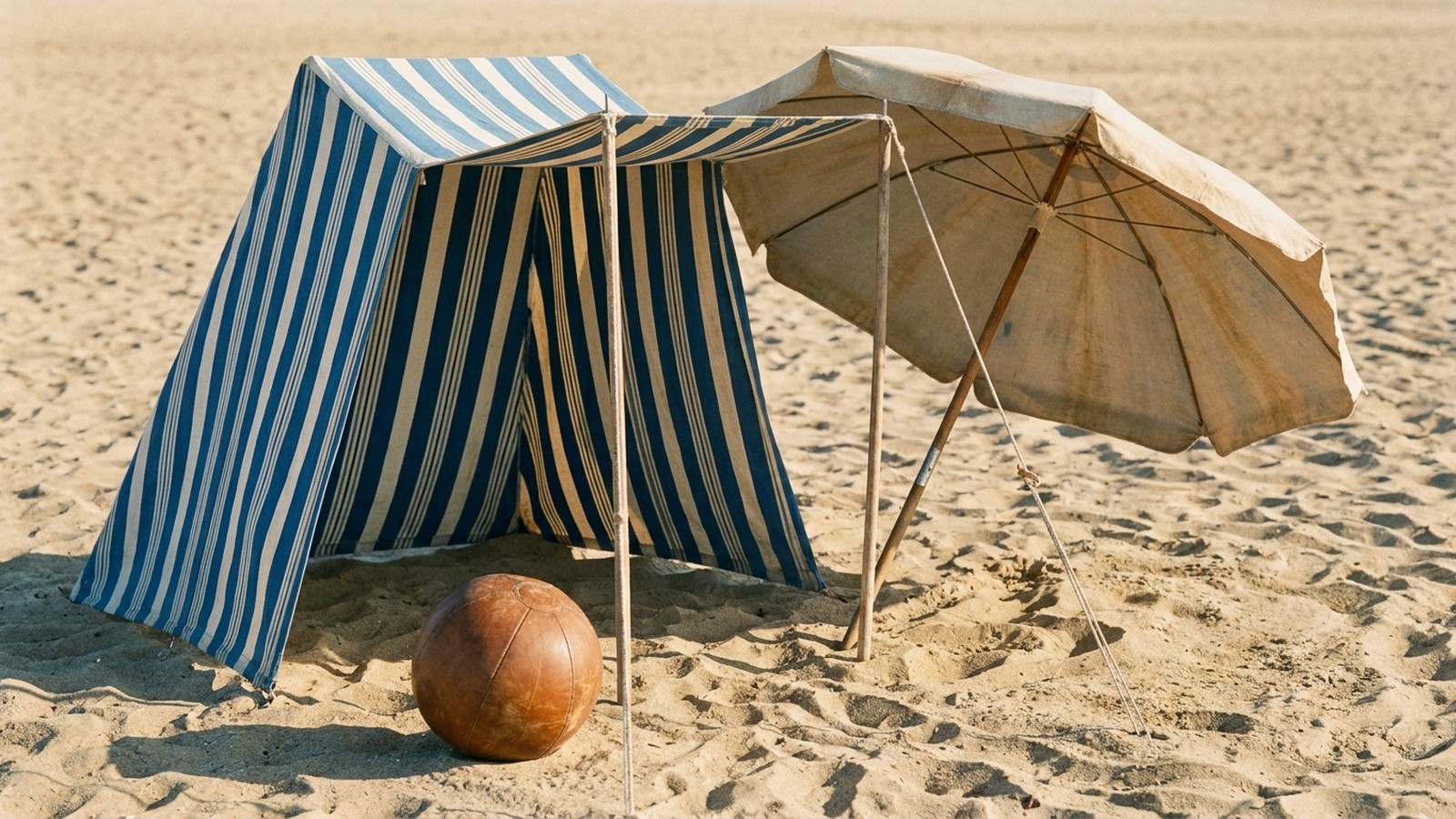 Une plage familiale d'autrefois avec une vieille tente de plage rayée et un parasol