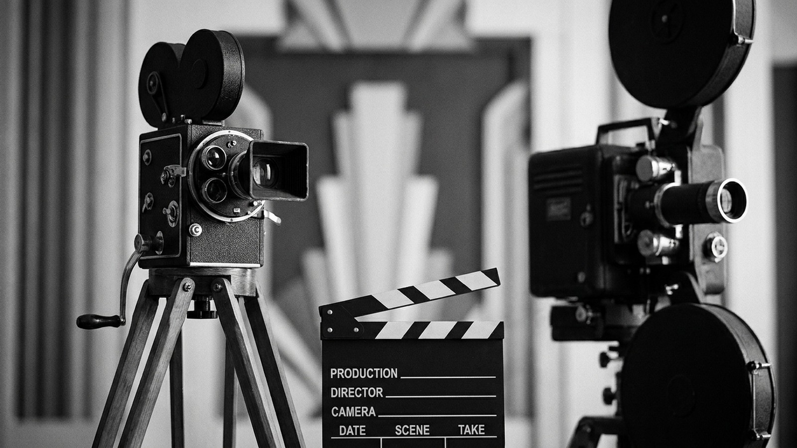 Un plateau de tournage en noir et blanc évoquant le cinéma muet des années 1920 : caméra à manivelle ancienne sur trépied, clap de cinéma et projecteur de studio