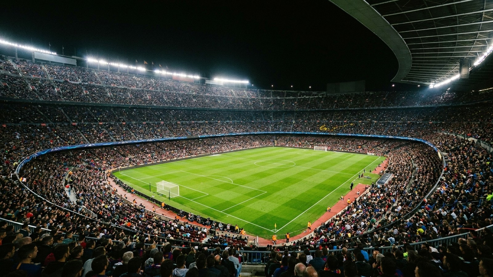 Un grand stade de football la nuit sous les projecteurs avec une pelouse verte et des tribunes