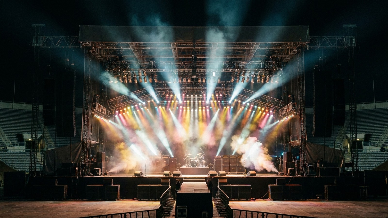 Un grand stade de concert rock la nuit avec une scène illuminée et des projecteurs